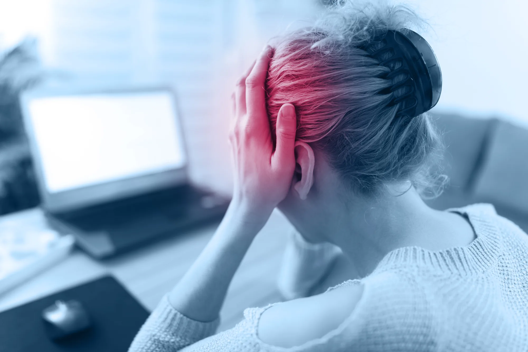 A woman at her desk easing a tension headache